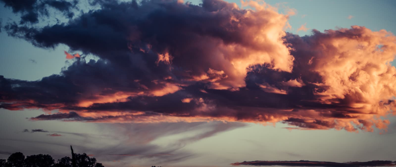 Banda amplia de nubes con profundidad azul marino oscura y un borde dorado sutil.